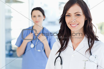 Smiling nurse accompanied by her colleague in the background
