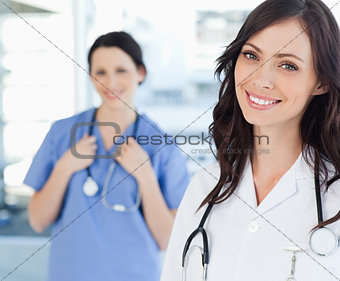 Smiling nurse standing upright while leaning her head to the sid