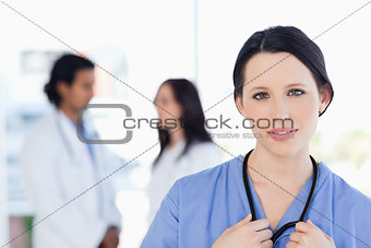 Serious medical intern looking at the camera while her team is b