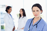 Calm nurse standing upright with her stethoscope around her neck