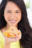 Close up of a woman smiling holding pizza to her mouth