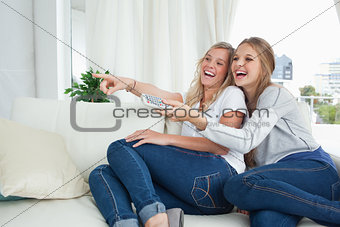 Girls laughing on the couch as they watch tv