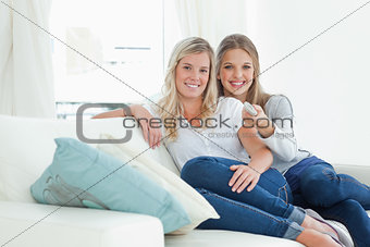 A pair of girls with a tv remote as they look at the camera