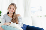 Smiling girl lying on the couch looking at the camera