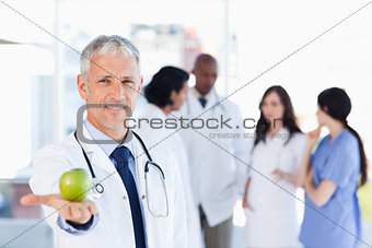 Mature doctor holding an apple in his right hand