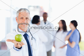 Mature doctor holding a green apple