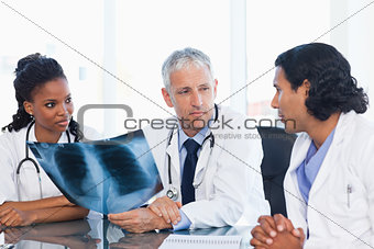 Mature doctor looking at an x-ray with two members of his team