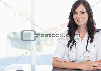 Young smiling doctor sitting at the desk near a clipboard