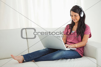 Latino student wears earphone using a laptop