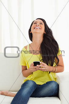 Happy Latino looking up while holding her cellphone