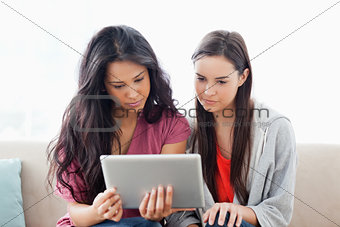 Two women on the couch looking at a tablet together