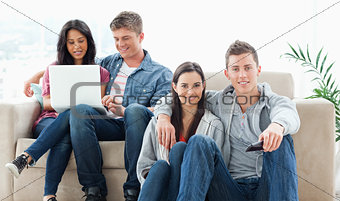 A couple sitting on the ground with a remote while another coupl
