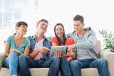A laughing group of friends watch the tablet pc