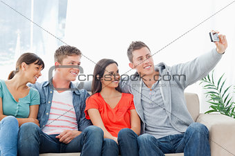 A group of friends pose for a photo while on the couch