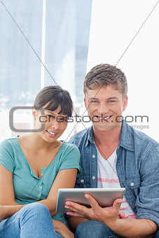 Close up of a smiling couple with a tablet pc looking into the c