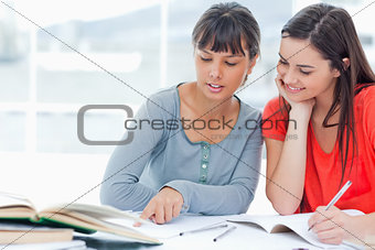 Two girls help one another as they study