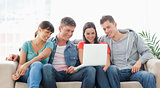 A smiling group of friends watching a show on the laptop togethe