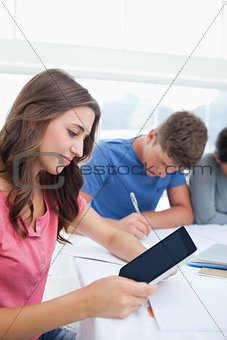 A woman looking at her tablet while studying