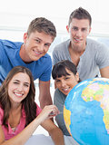 A group of friends beside a globe looking into the camera