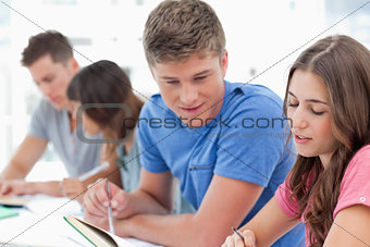 Side view of people studying as one guy helps a girl