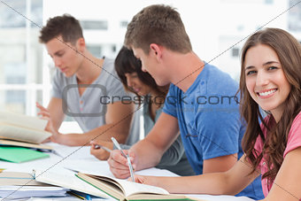 A side view of people studying as one girl looks into the camera