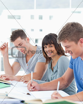 A smiling girl looking at the camera while her friends work