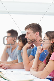 Four students listening in class while one looks tired