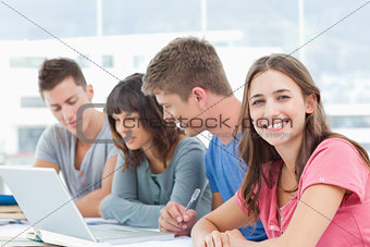 Three students look into the laptop as the fourth student looks 