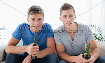 Two guys looking into the camera with beer in hand