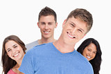 A man smiling with his head tilted and his friends behind him