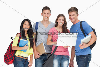 A smiling group of students holding a laptop while looking at th