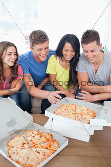A laughing group of friends gathered around some pizza