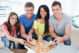 A group of friends taking a slice of pizza each as they look at 
