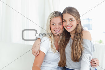 A pair of sisters hug each other as they look into the camera
