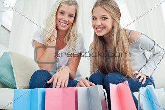 Smiling girls looking at the camera with bags by their feet