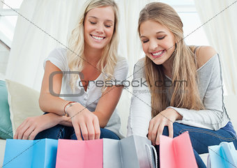 Smiling girls looking into the bags below them