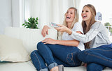 Girls sitting on the couch laughing at the tv