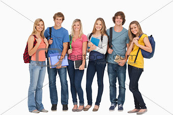 Smiling students wearing backpacks and holding books in their ha