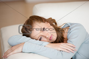 Woman lying on a sofa crossing her arms 