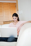 Woman using a laptop while sitting on a sofa