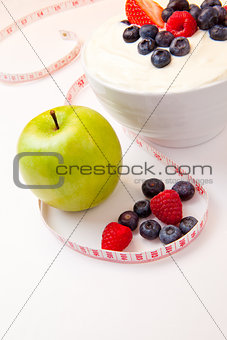 Apple and bowl of berries cream and a tape measure 