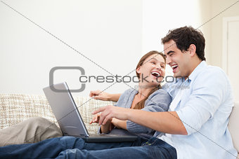 Couple laughing while typing on a computer