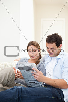 Young Couple embracing while reading a newspaper 