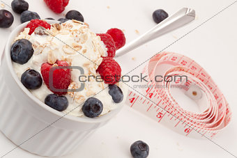 Jar of fruits and whipped cream with spoon and tape measure 