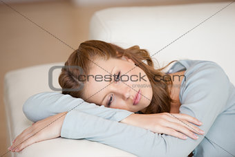 Woman lying on a sofa crossing her arms looking down