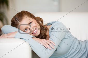 Smiling Woman crossing her arms while lying on a sofa 