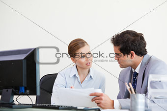Colleagues talking while holding a sheet