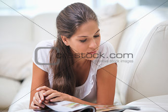 Woman lying on a sofa while reading a book