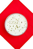 Close up of a bowl of dip with herbs on a red napkin against a w