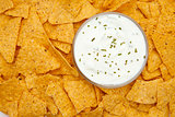 Bowl of dip with herbs surrounded by nachos